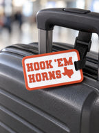 Custom 3D printed orange and white Hook Em Horns luggage tag on suitcase