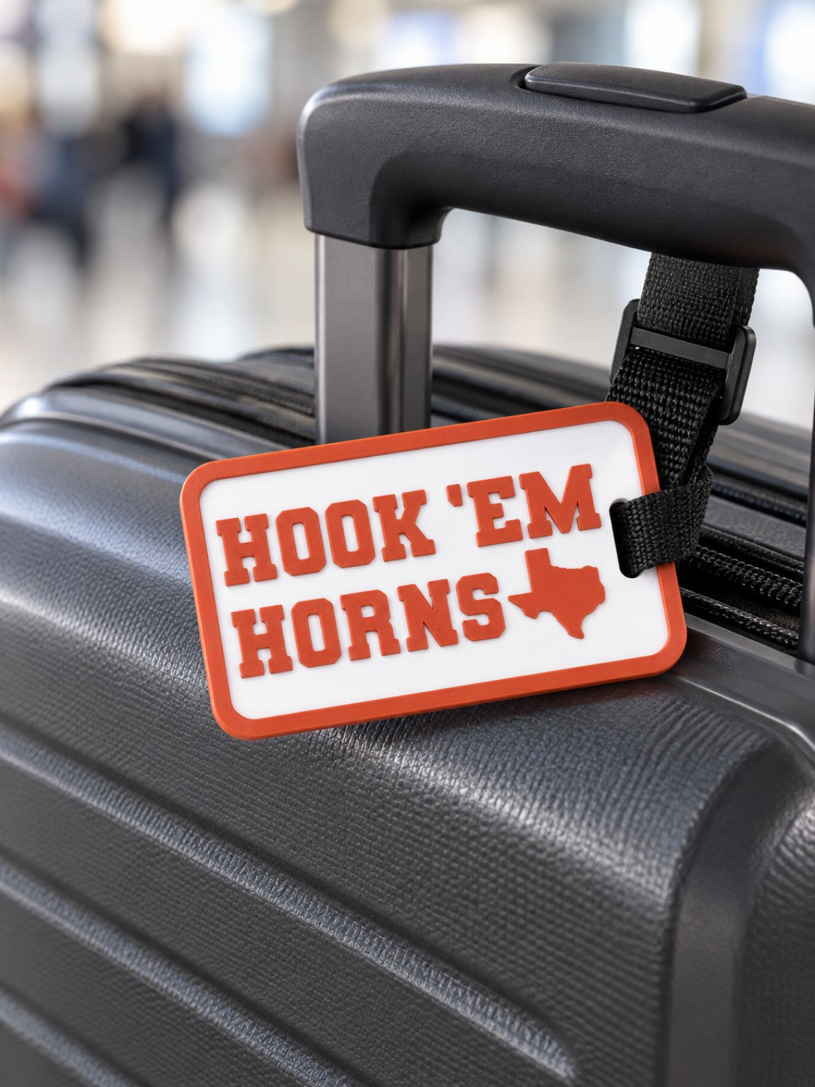 Custom 3D printed orange and white Hook Em Horns luggage tag on suitcase